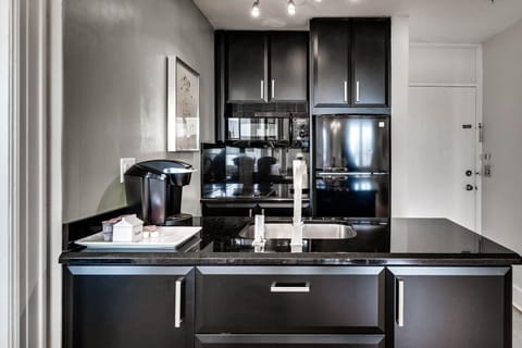 Kitchenette with microwave, fridge, Keurig coffee maker, glasses, plates, and cutlery