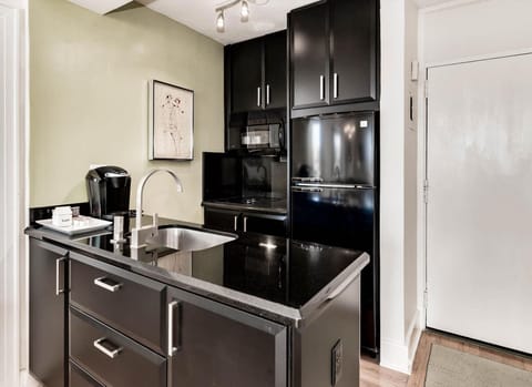 Kitchenette with microwave, fridge, Keurig coffee maker, glasses, plates, and cutlery