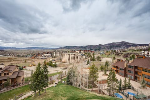 Scenic mountain resort development with modern condominiums nestled among rolling hills and evergreen forests under dramatic Colorado skies.