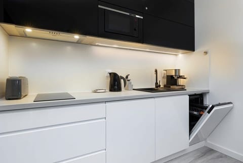 A modern kitchen with white furniture and appliances such as a dishwasher, fridge and hob that ensure home-cooked meals are prepared.