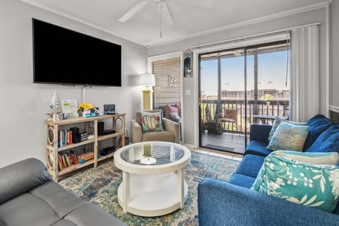 Living area with a sectional, wall TV and doors to the balcony at Tilghman Beach & Racquet Club 346, a 3-bedroom rental