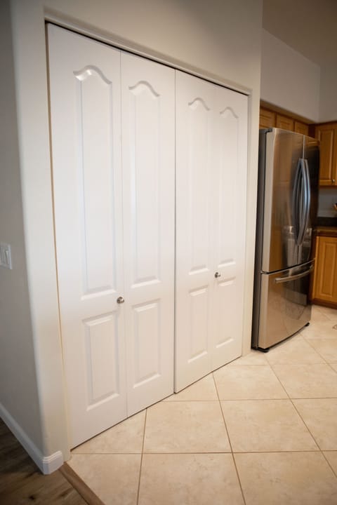 Kitchen pantry roomy with shelving and bifolding doors.