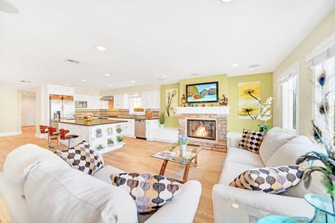 The main living area is located on the ground floor and includes two sofas, cable TV, fireplace, and kitchen and dining areas beyond.