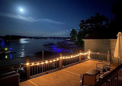 String lights, outdoor seating, and moonlit water create the property's signature evening gathering space above the lake.