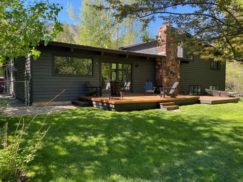 Back of house with deck and 6 adirondack chairs.