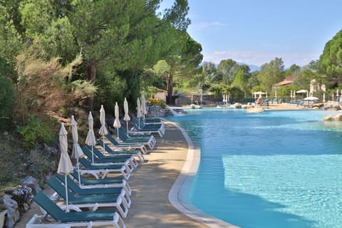 Pool deck lined with umbrellas and loungers, steps from the restaurant and game room on-site.