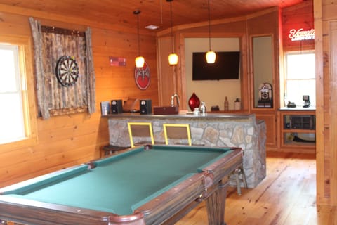 Large game room with pool table, darts, bar and television.