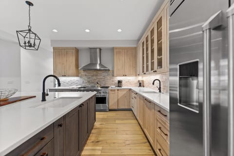 Full kitchen with stainless steel appliances, 2 sinks, and a large kitchen island with breakfast bar seating for casual dining.