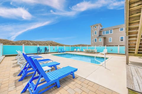 Beachside private pool framed by sand dunes and coastal architecture, offering a peaceful retreat under open skies.