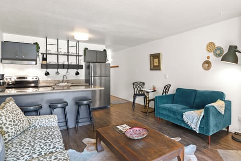 The living room offers two colorful couches and an open concept kitchen.