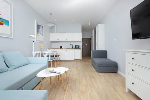 A bright and cozy space featuring two matching sofas, a small dining table with chairs, and large windows letting in natural light.
