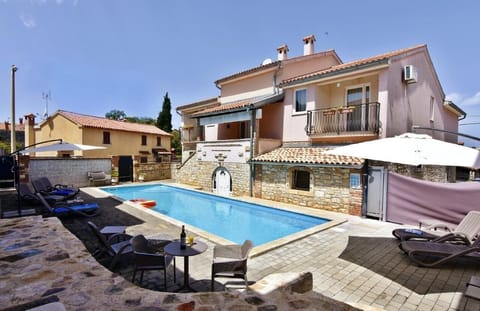 The exterior of the house and the pool area with deck chairs and umbrellas