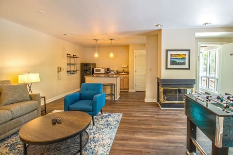 Lower level open floor plan includes living area, foosball table, partial kitchen and electric fireplace