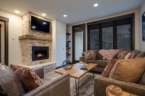 Sink into plush seating by your crackling fireplace, where warm stone and cozy textures create the perfect retreat for relaxing evenings.