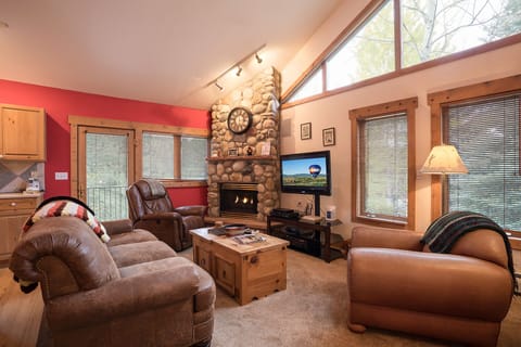 Sink into plush leather seating by your crackling stone fireplace, where natural light streams through soaring windows creating the perfect mountain retreat ambiance.