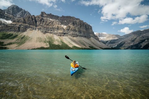 Paddle through crystal clear waters with towering mountains guiding your journey.