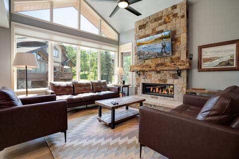 Sink into plush leather seating by your crackling stone fireplace, where soaring windows frame mountain views for ultimate relaxation.