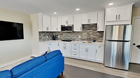 Full Kitchen with Cabinets, Quartz counters, Fridge, Microwave, countertop cooktop; no oven.