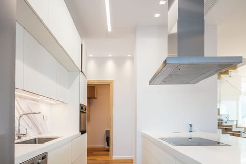 The kitchen features sleek white surfaces, and wall-mounted appliances.
