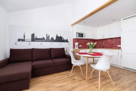 Bright and spacious studio interior featuring a comfortable sofa, dining table, and stylish red kitchen backsplash.