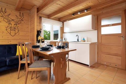 A spacious open-plan kitchen and dining area with wooden walls and ceiling, creating a cozy yet functional environment.