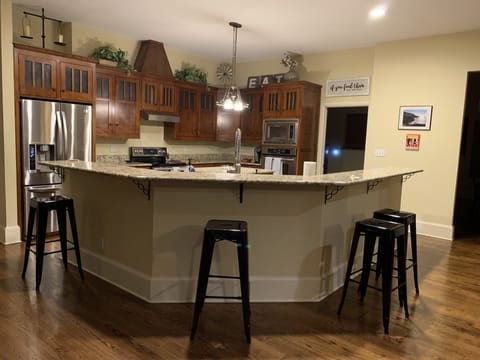 Large eat in kitchen with stainless steel appliances, island and four stools.