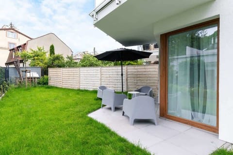 Backyard with patio chairs, umbrella, and green grass.
