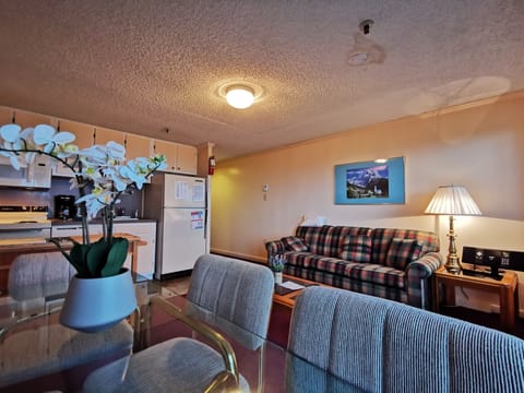 
A retro-style space with plaid sofa, soft lighting, and dining area.
