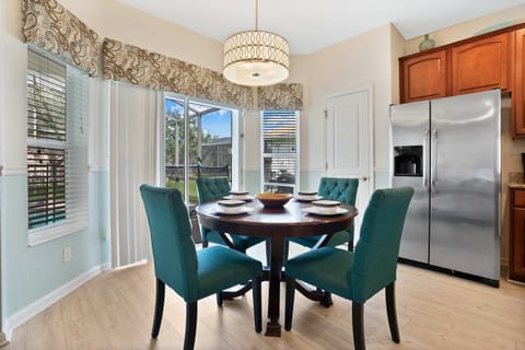 Charming breakfast nook with teal chairs, natural light, and views of the backyard.
