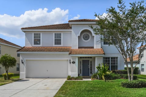 Stunning Mediterranean-style villa with tile roof, two-car garage, and lush landscaping.
