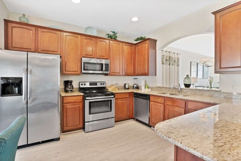 Fully equipped kitchen with stainless steel appliances, granite countertops, and warm wood cabinets.