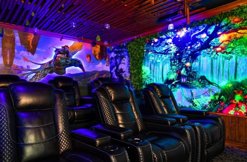 Immersive home theater with luxurious leather recliners and vibrant, fantasy-themed wall art.