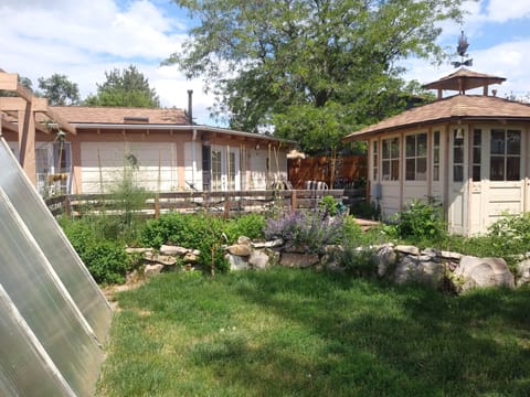 Gazebo with Hot Tub, Backyard Gate, Patio, Chairs, Fire Pit, Pond, Greenhouse.