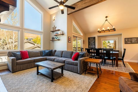 Living Room with Samsung smart tv, plush sectional sofa, gas fireplace, floor to ceiling windows, and separate sitting area with two leather armchairs