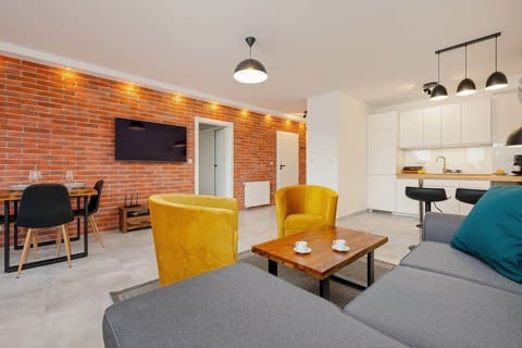 Widok od strony szarej sofy na ścianę  z cegłą w całej okazałości.