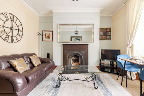 Our stylish living room with two leather sofas, a mechanical clock, a sleek coffee table, and modern amenities like a heater, air purifier, and wall mirror. Your cozy retreat awaits!