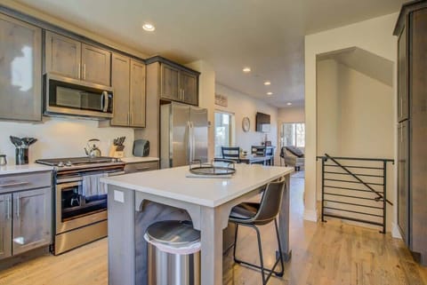 The kitchen centers around a long island with seating, paired with stainless appliances and warm cabinetry. Whether prepping a meal or lingering with coffee, the open layout keeps everything within reach and conversation flowing.