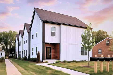 Exterior of modern white and gray townhouse at dusk with purple sky