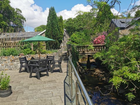 Idyllic riverside terrace with outdoor dining and views of the woodland garden