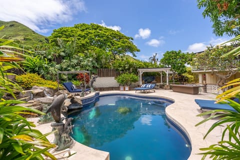 Immerse yourself in tropical paradise at this stunning private pool, nestled beneath swaying palms and a majestic shade tree, with dramatic mountain views completing your serene Hawaiian escape.