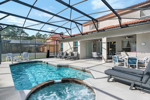 Large swimming pool and hot tub with extended pool deck, sun beds, and a lake view.