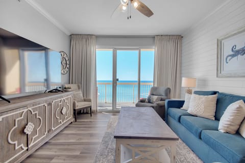 Living Room - Indulge in seaside luxury and comfort with this bright living room, featuring plush furniture including 2 recliners, a large flat-screen TV, and a private balcony over the beach. 