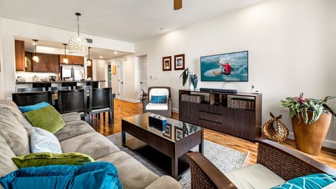 The living area includes a sofa sleeper, wall-mounted TV, and coffee table.