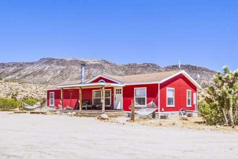 Red House with a shaded front porch and desert mountain views.