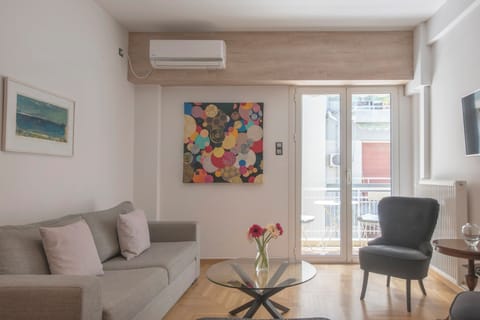 Main living area opening onto balcony: AC, smart TB, speaker, adjoining kitchen