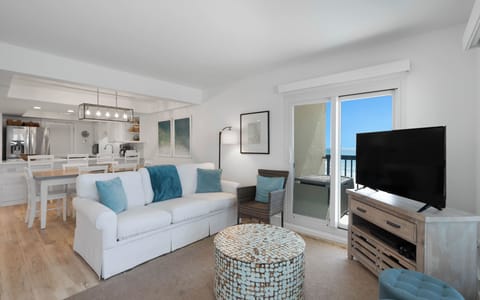 Sink into plush seating while ocean breezes flow through your private balcony doors in this bright, coastal-inspired living space.