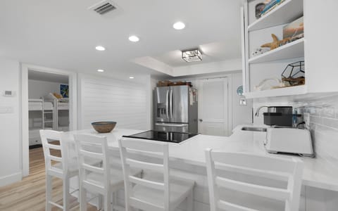Your modern kitchen invites culinary adventures with pristine white countertops, stainless steel appliances, and a breakfast bar perfect for morning coffee.