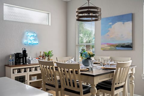 Bright dining area with a rustic table set for six adjacent to the coffee bar.