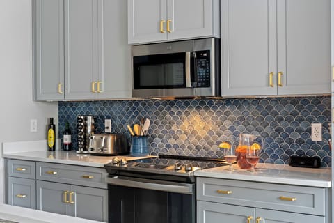 Modern kitchen with sleek cabinetry, gold accents, and blue backsplash.