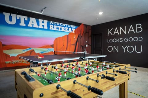 Get ready for fun in the garage game room featuring two custom murals, a ping pong table, a foosball table, pop-a-shot, and darts